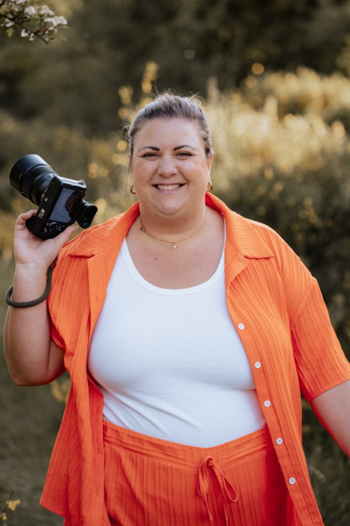 Fotografin mit Kamera lachend auf Wiese